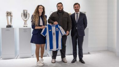 Imagem dos representantes do FC Porto e da Luna Esports juntos enquanto seguram a camisola do FC Porto. Uma coleção de troféus de futebol em pedestais está ao fundo