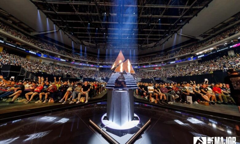 Imagem do troféu BLAST.tv Austin Major 2025 iluminado por luz branca e chamas do palco. Uma multidão lotada está ao fundo