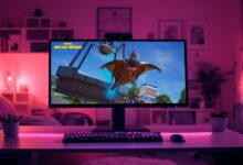 Um monitor de computador exibindo o jogo Fortnite Battle Royale em uma sala com iluminação neon roxa